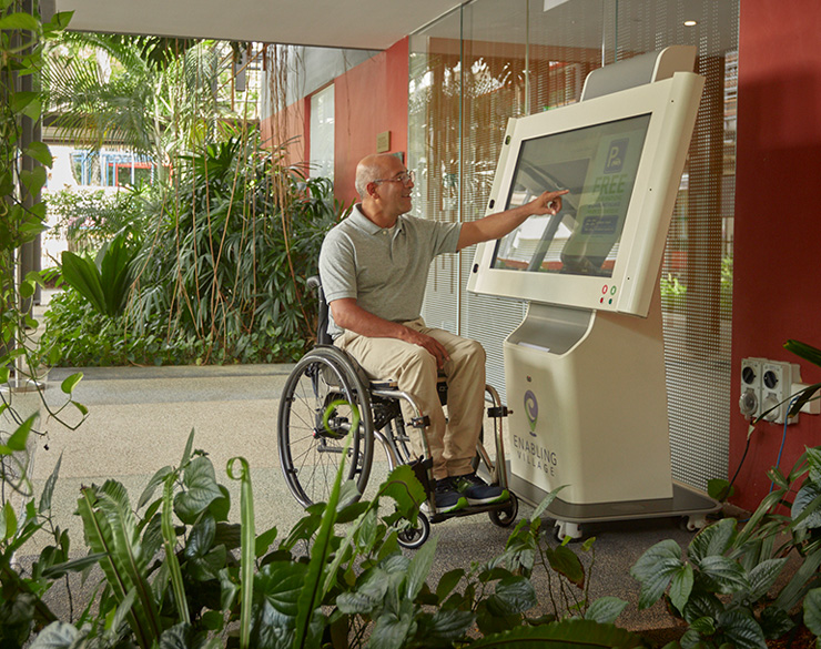 A wheelchair user using the digital information kiosk outside the Nest block at the Enabling Village.