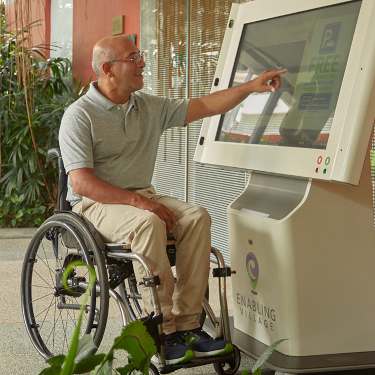 A wheelchair user using the digital information kiosk outside the Nest block at the Enabling Village.