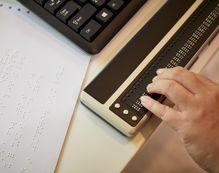 A hand touches the Brailliant 80, a Braille refreshable display.