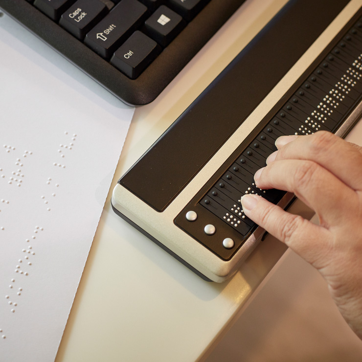 A hand touches the Brailliant 80, a Braille refreshable display.