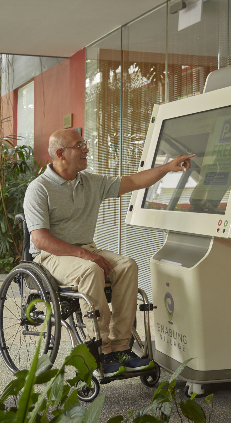 A wheelchair user using the digital information kiosk outside the Nest block at the Enabling Village.