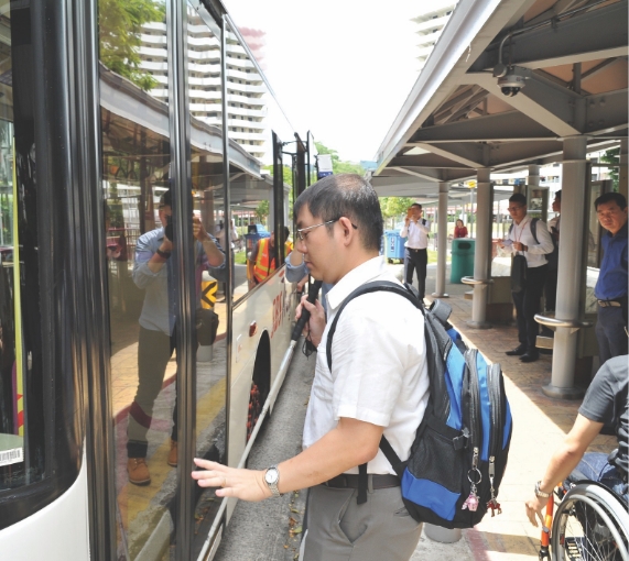 A person with visual impairment boarding the bus with the use of MAVIS.