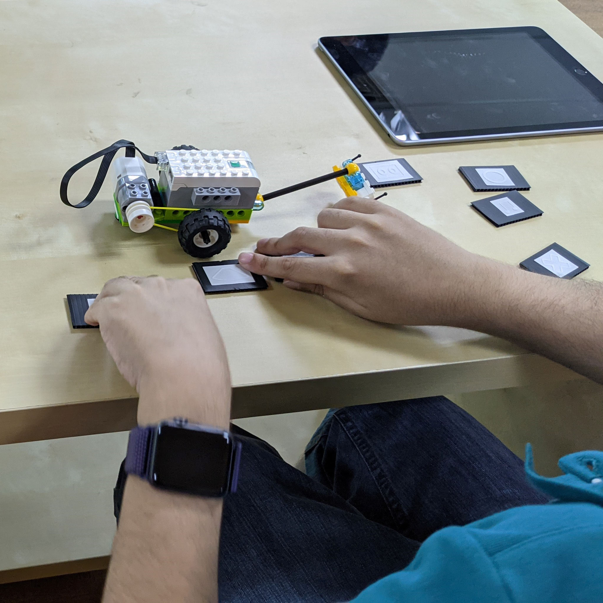 A student with visual impairment participating in one of two pilot workshops on coding and robotics, using blocks from Lego WeDo kits and printed tactiles to represent coding blocks in the Lego WeDo app.