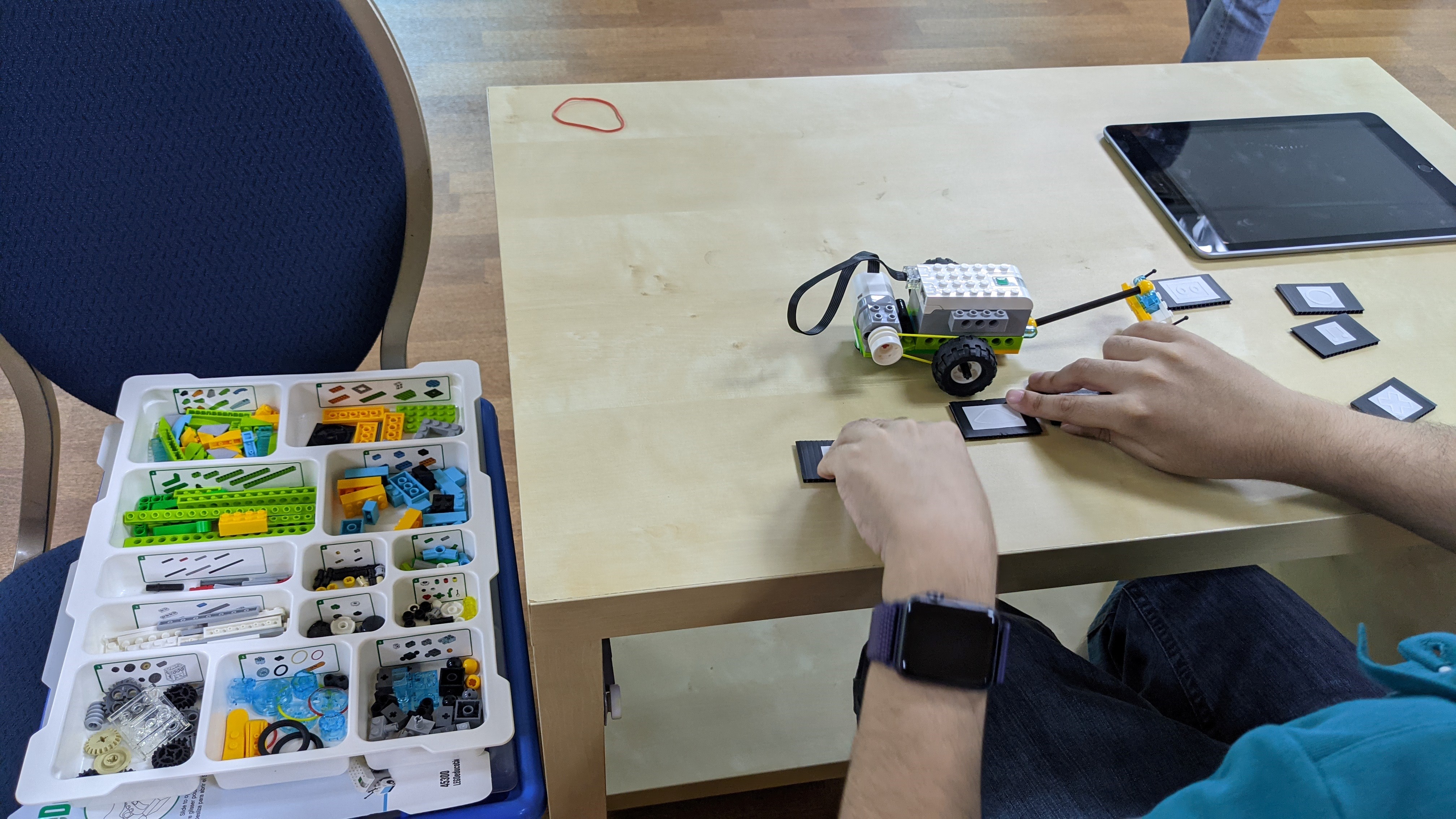 A student with visual impairment participating in one of two pilot workshops on coding and robotics, using blocks from Lego WeDo kits and printed tactiles to represent coding blocks in the Lego WeDo app.