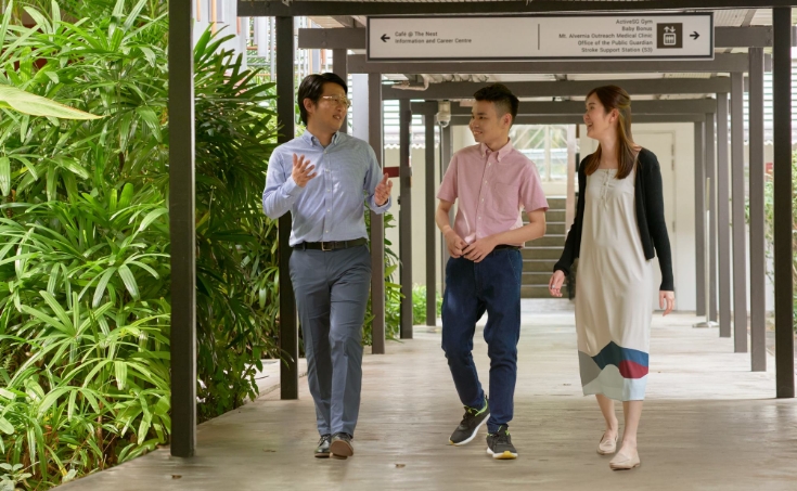 A professional speaking with two other professionals, as they walk down a pathway.