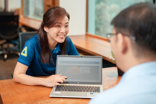 A SG Enable staff showing information on her laptop to a person with disability.
