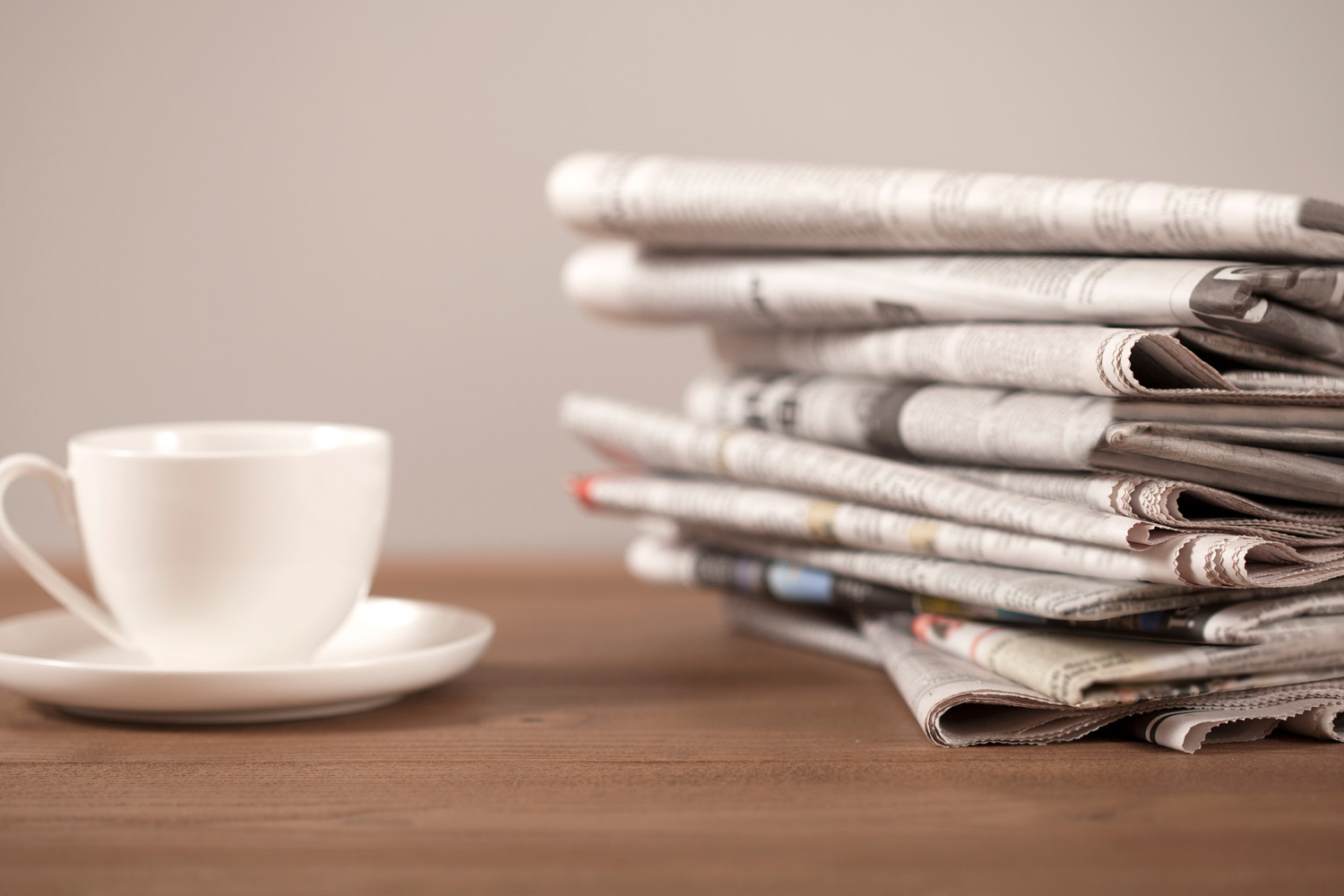 Photo of a stack of newspapers and a white coffee cup