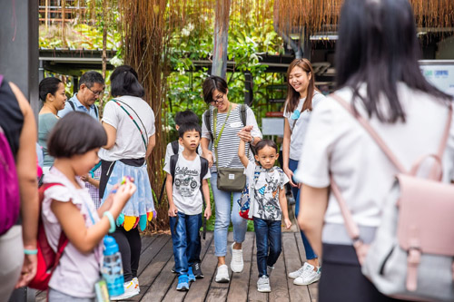 A mother holding the hands of her two children walking through a crowd at the CAREcarnival.