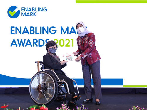 President Halimah presenting a wheelchair user with an award at the Enabling Mark Awards 2021.