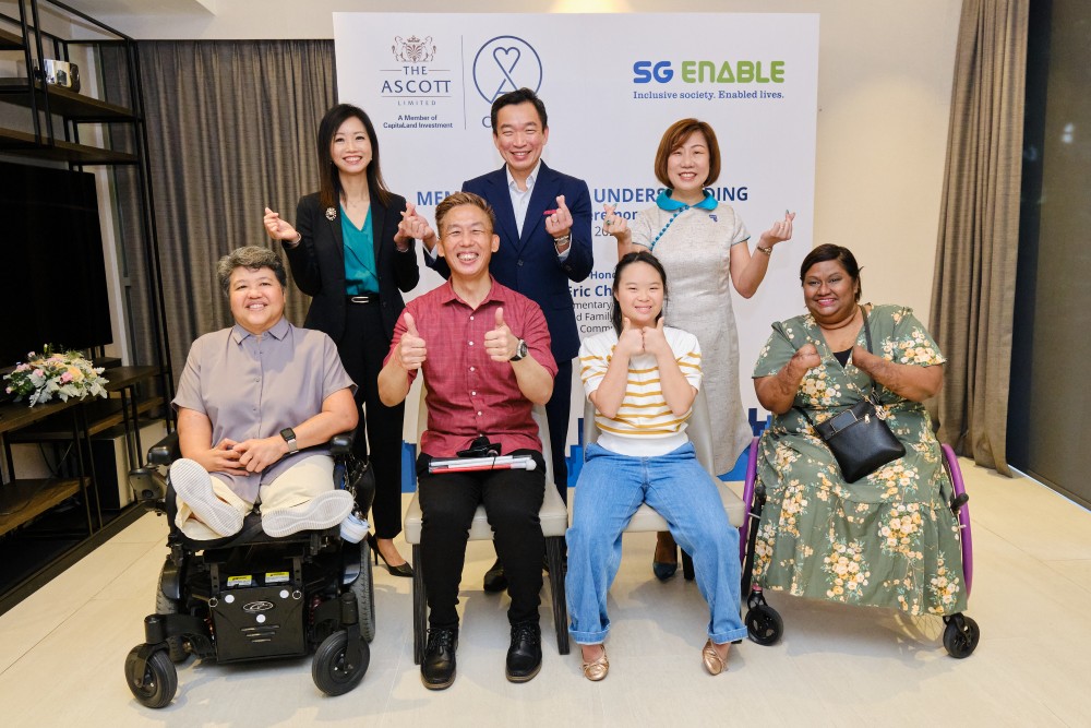 Group photo of Mr Eric Chua, Ms Beh Siew Kim, Ms Ku Geok Boon, and a group of persons with disabilities smiling.