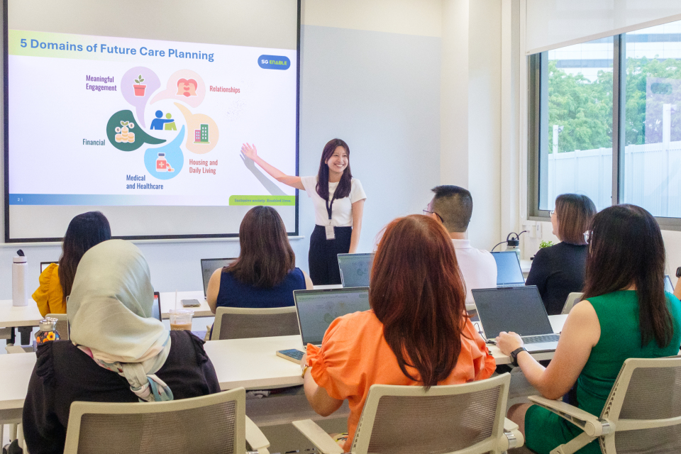 An SG Enable staff giving a briefing on caregiving to a group of caregivers.