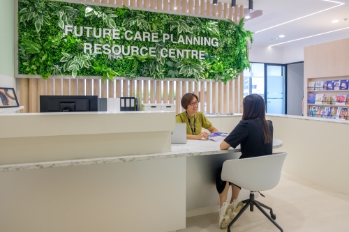 An SG Enable staff serving a caregiver at the counter of the Future Care Planning Resource Centre.