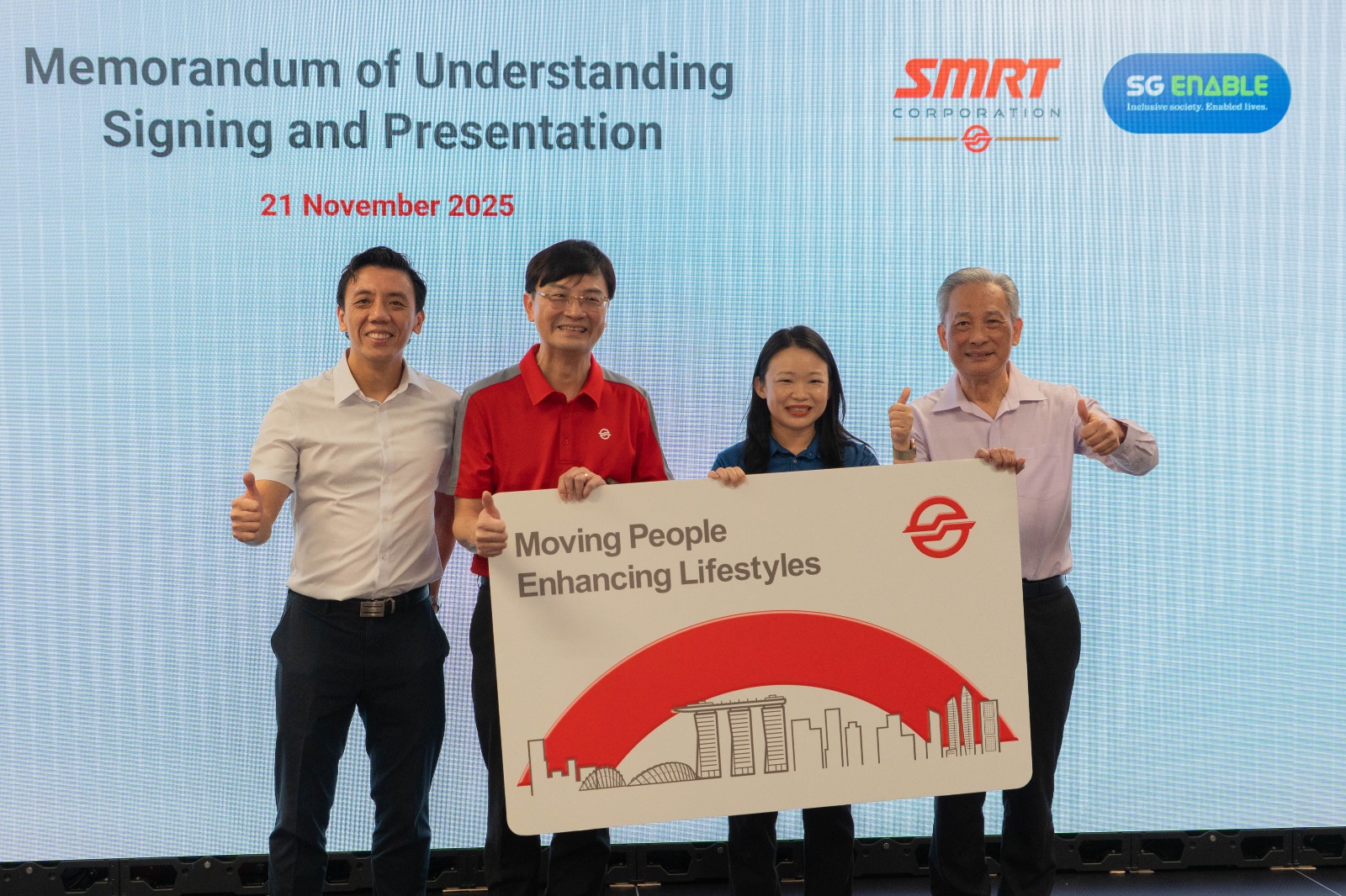 A group of 4 people standing on stage posing for photo with a SMRT banner.