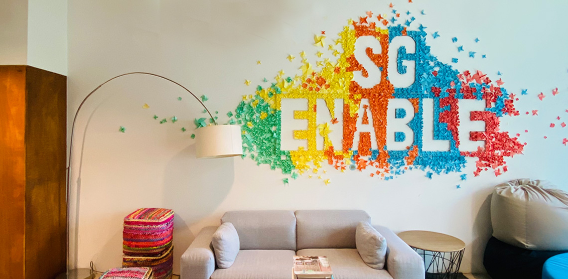 Interior of the SG Enable Office. A wall is decorated with vibrantly coloured paper decorations created by SG Enable staff.