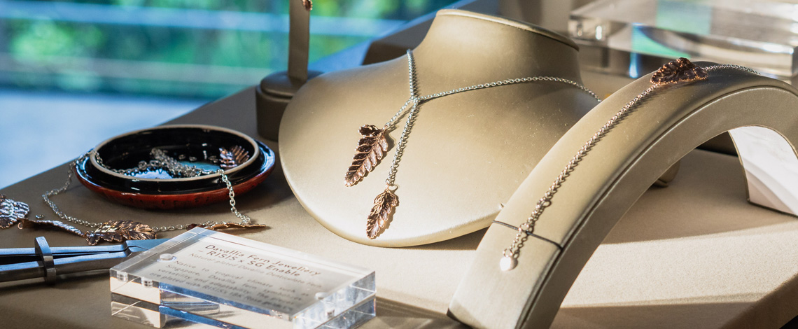 A set of silver leaf-themed jewelry on display, including a necklace, a bracelet, and earrings
