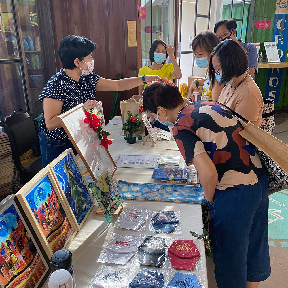 A few ladies at an arts and crafts booth. A lady with short hair is tending to the stall.