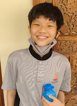 A boy smiling brightly at the camera, holding a blue water bottle in hand.