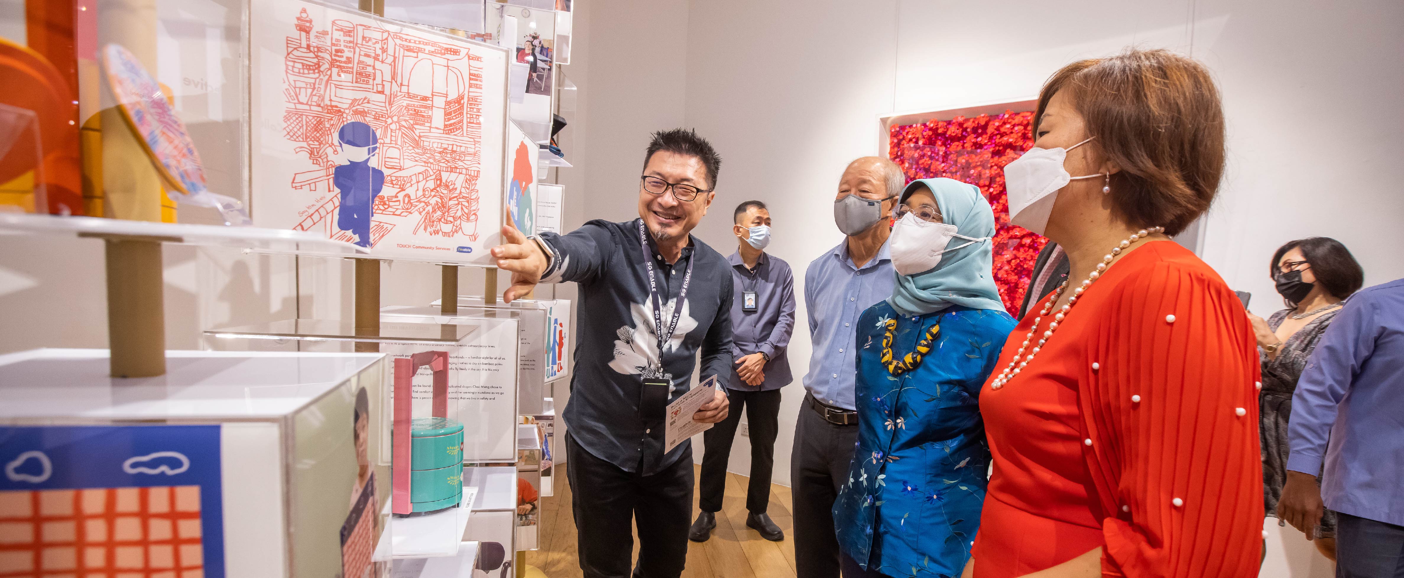 A SG Enable representative shares about the NDP exhibition with President, along with SG Enable's Chairman and CEO.