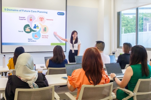 A classroom setting with a young female staff giving a talk on future care planning to a class of caregivers.