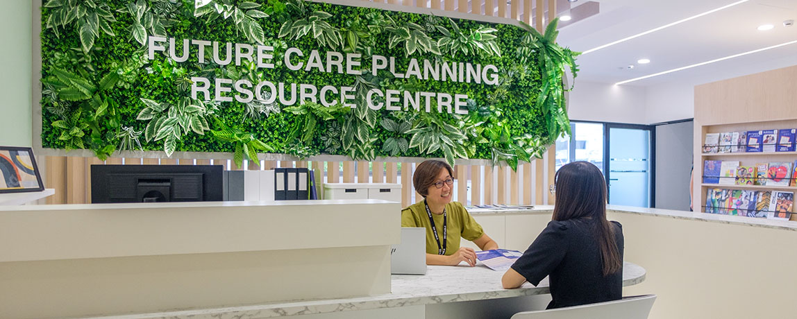 A staff at the Future Care Planning Resource Centre attending to a caregiver at the counter.