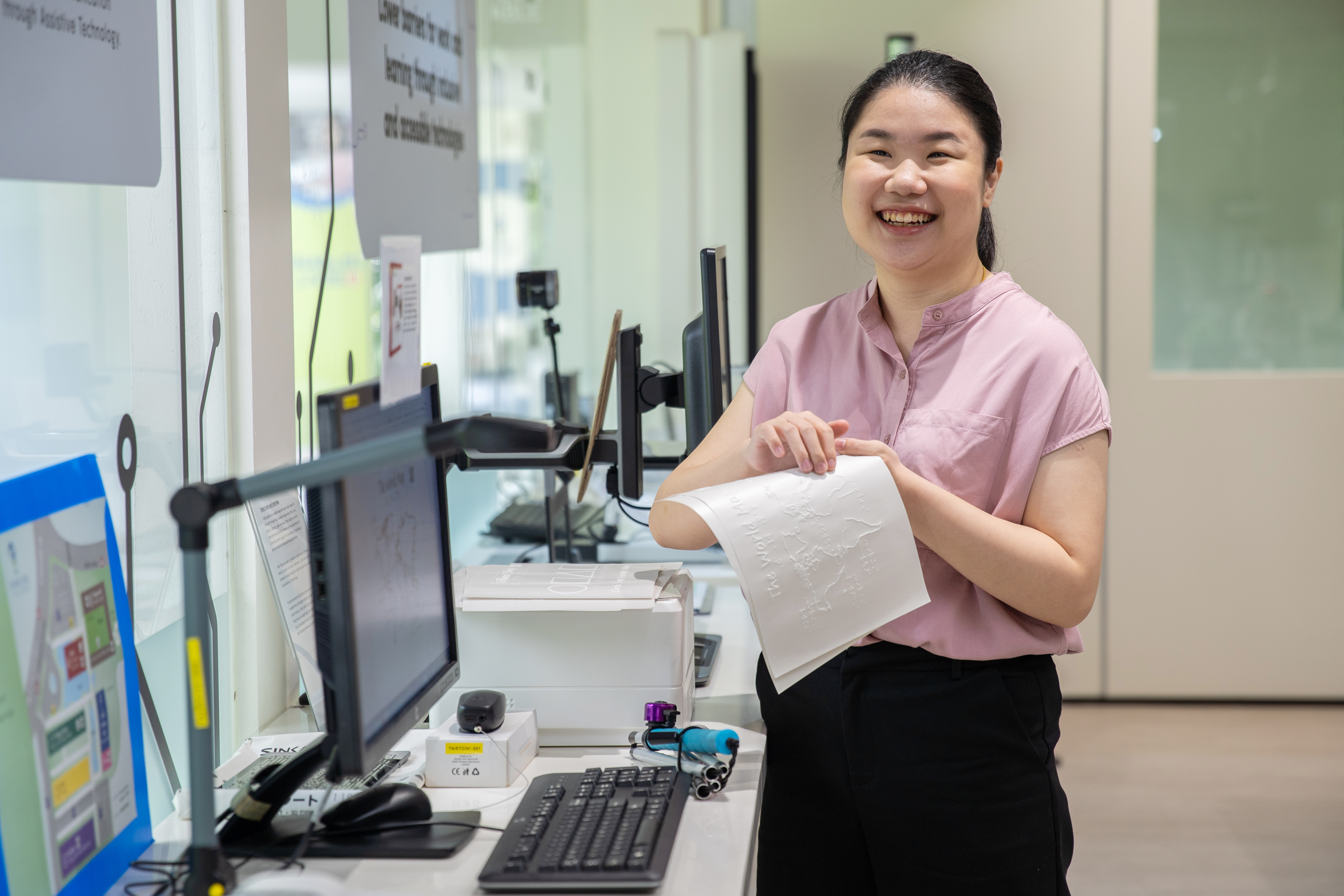 A smiling lady with visual impairment holding a tactile image printout from the TactPlus Tactile Printer.