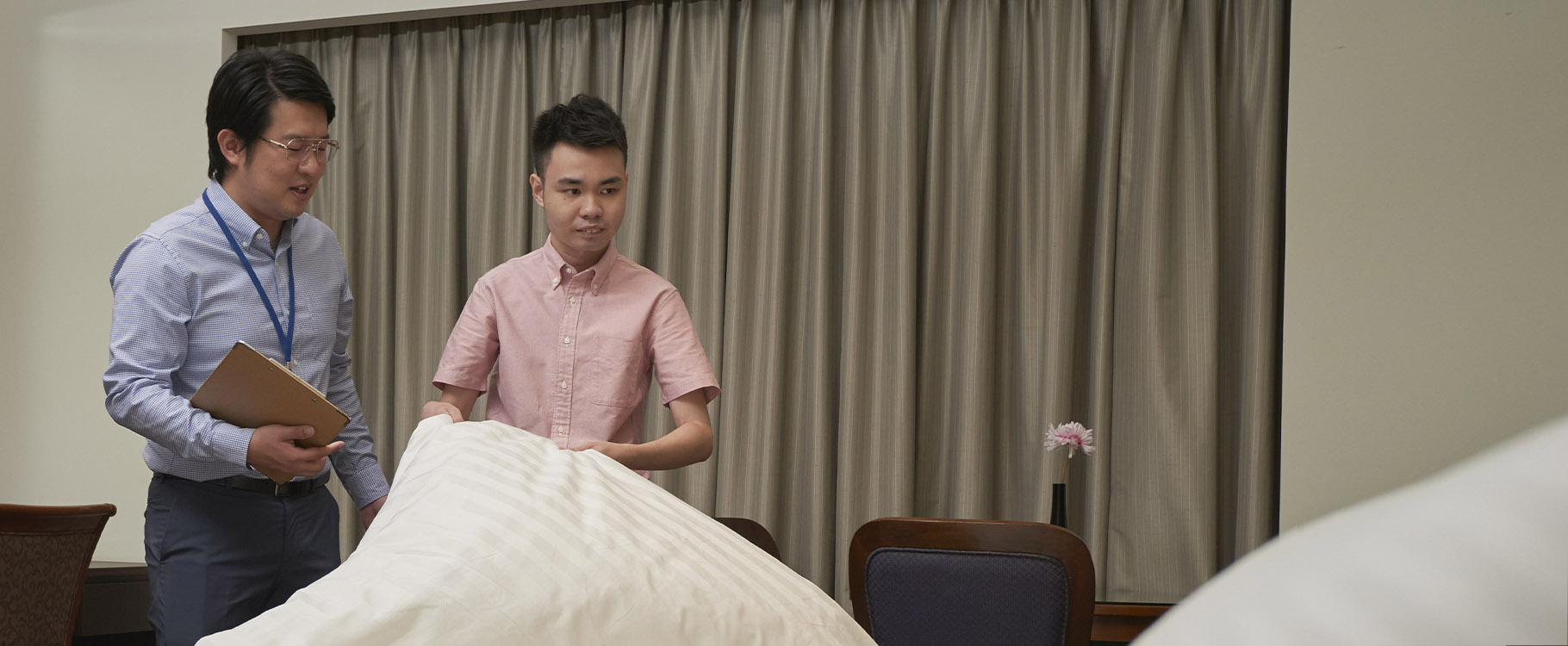 A professional guiding a person with disability in housekeeping duties such as neatly making beds.