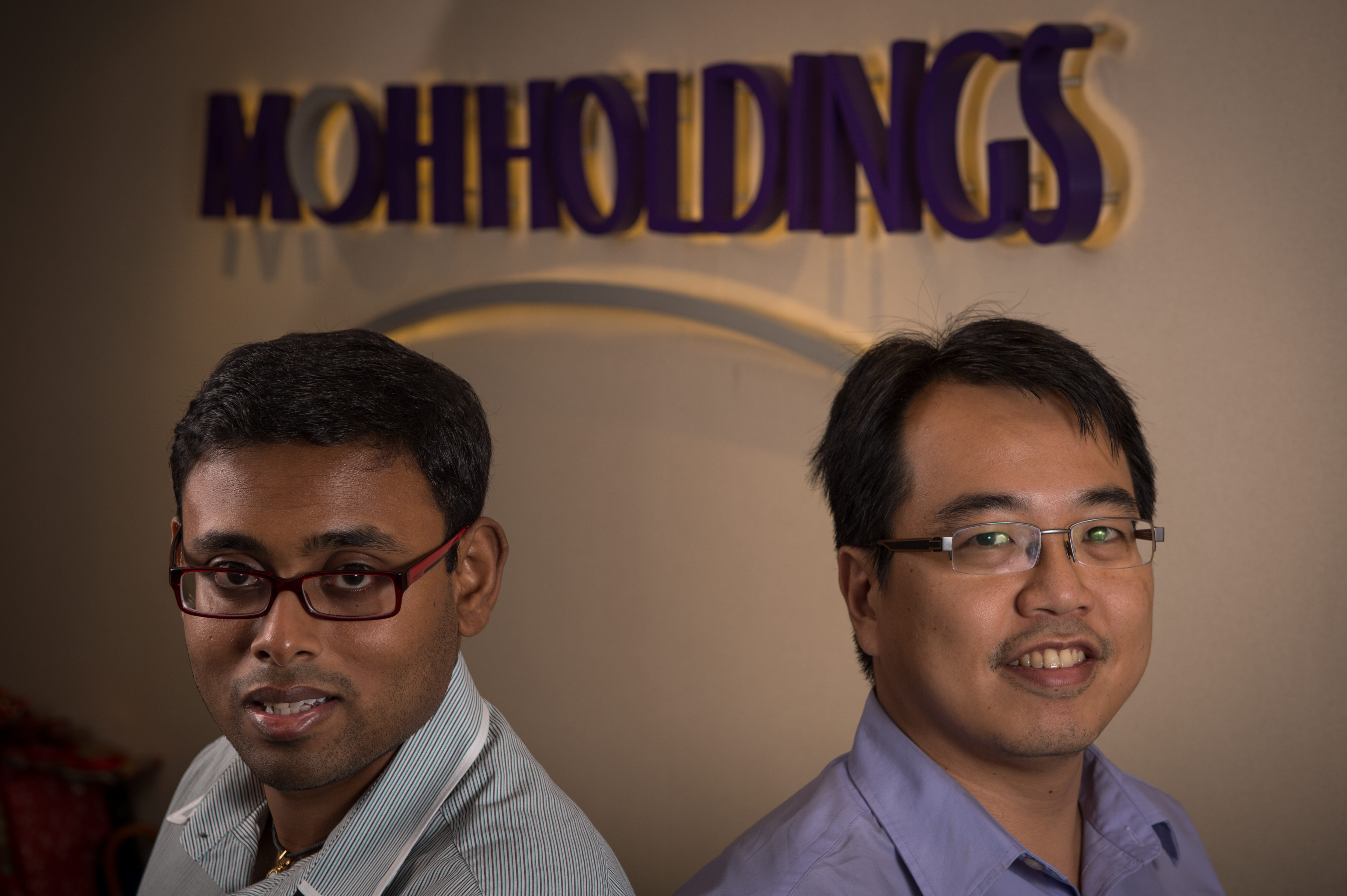 Two men smile for the camera, in front of the words 