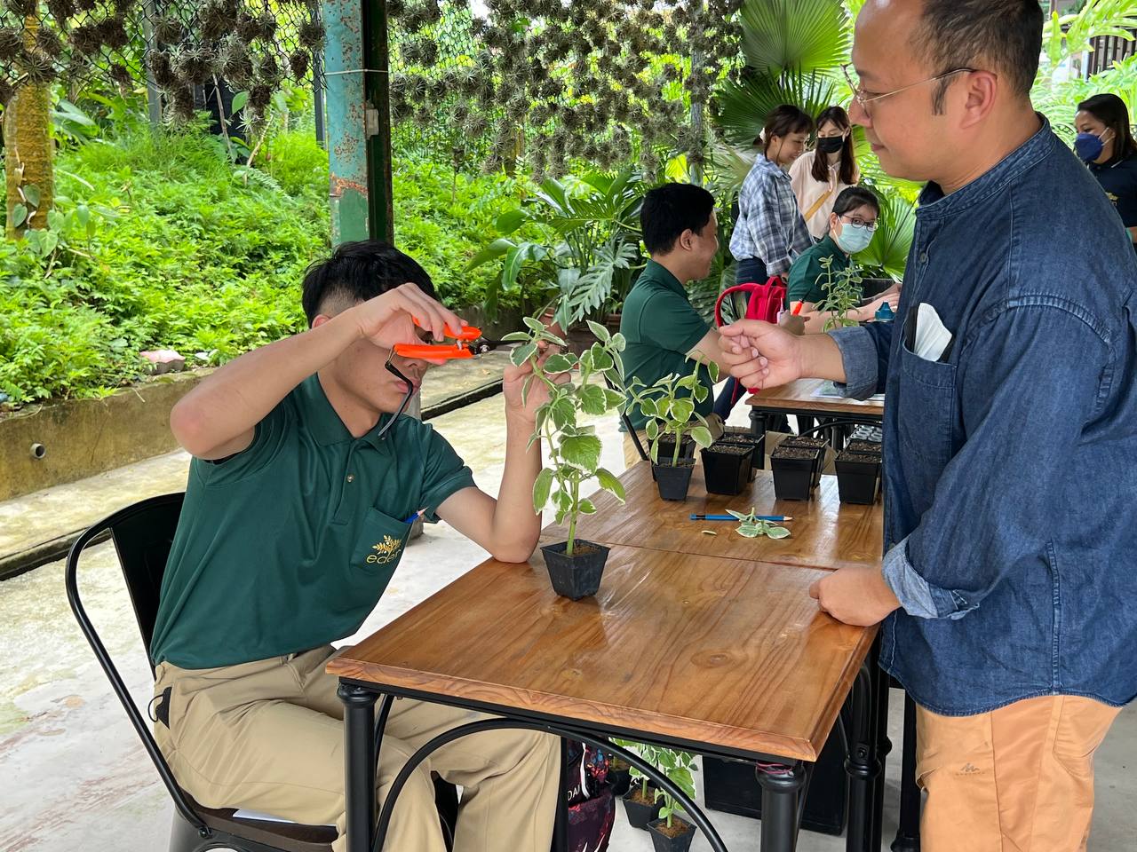 A staff from Tropic Planners guides a student from Eden School in growing seeds.