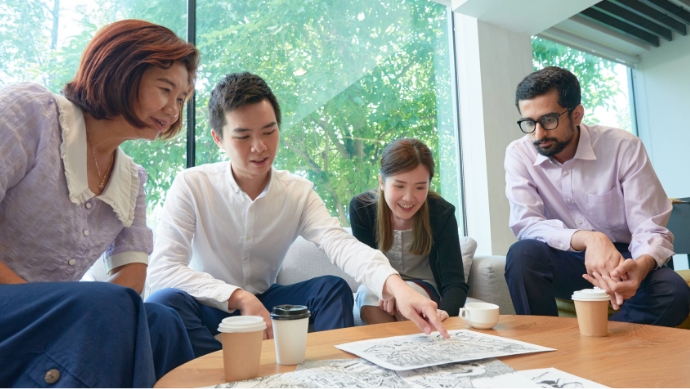 Four professionals looking at illustrations on papers on a table in front of them, as one professional points to the papers.