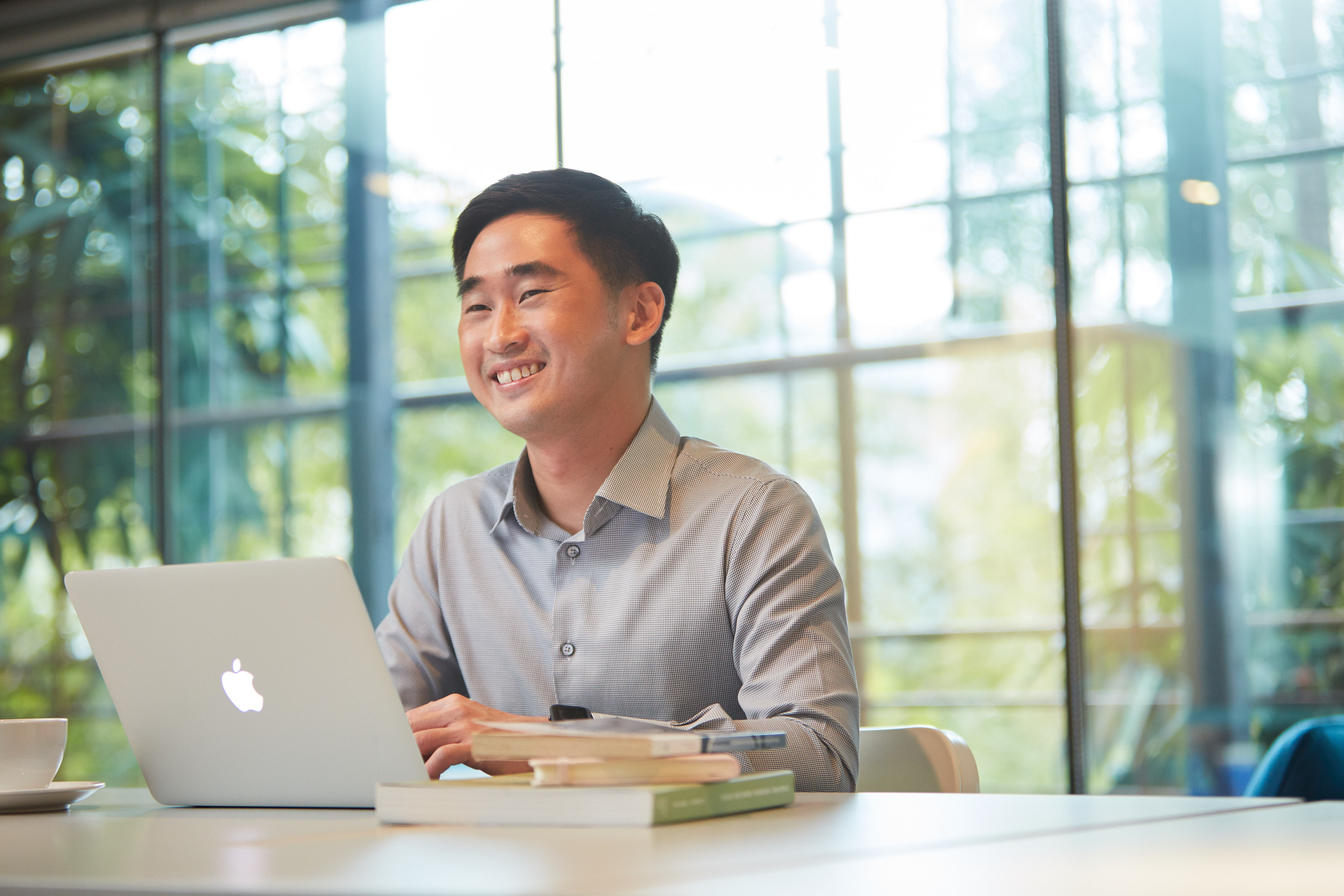 A man smiles as he works on his laptop.