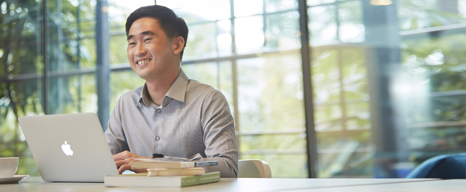 A man smiles as he works on his laptop.