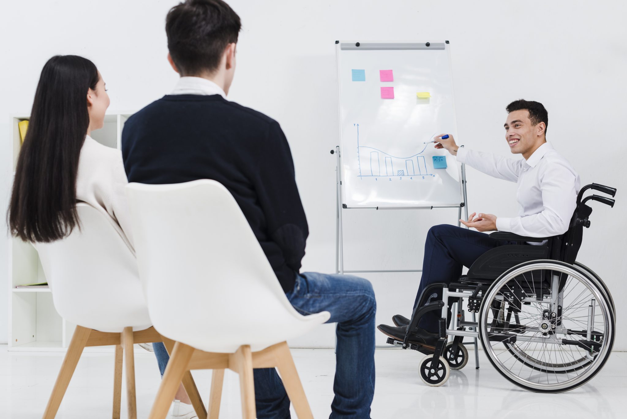 A male wheelchair user gives a presentation to his colleagues. Photo designed by Freepik.