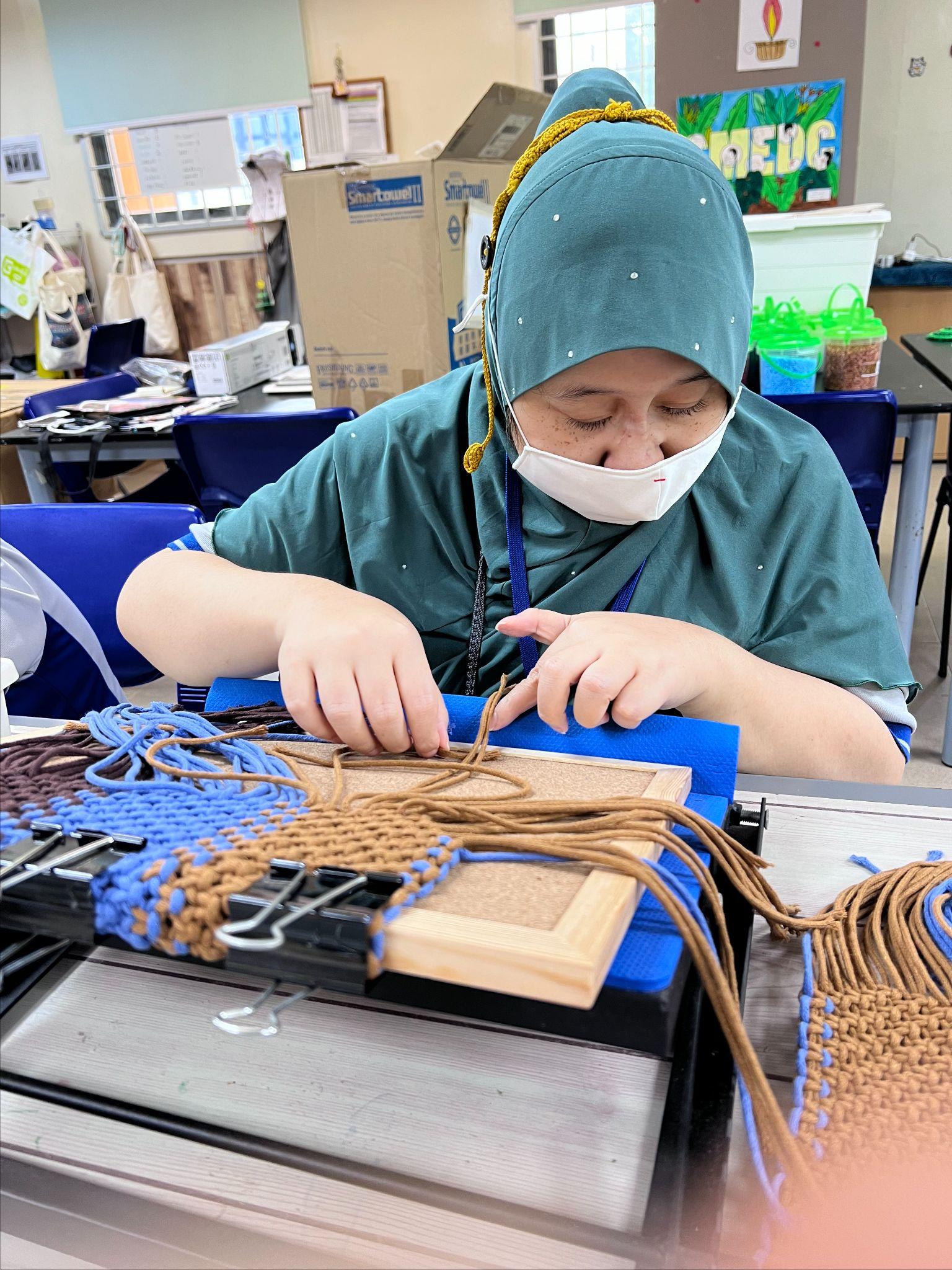 bd2 an individual working on an artwork using macrame knotting