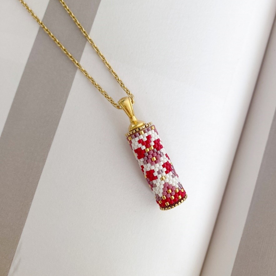 Necklace with a red and white cylindrical pendant and gold chain