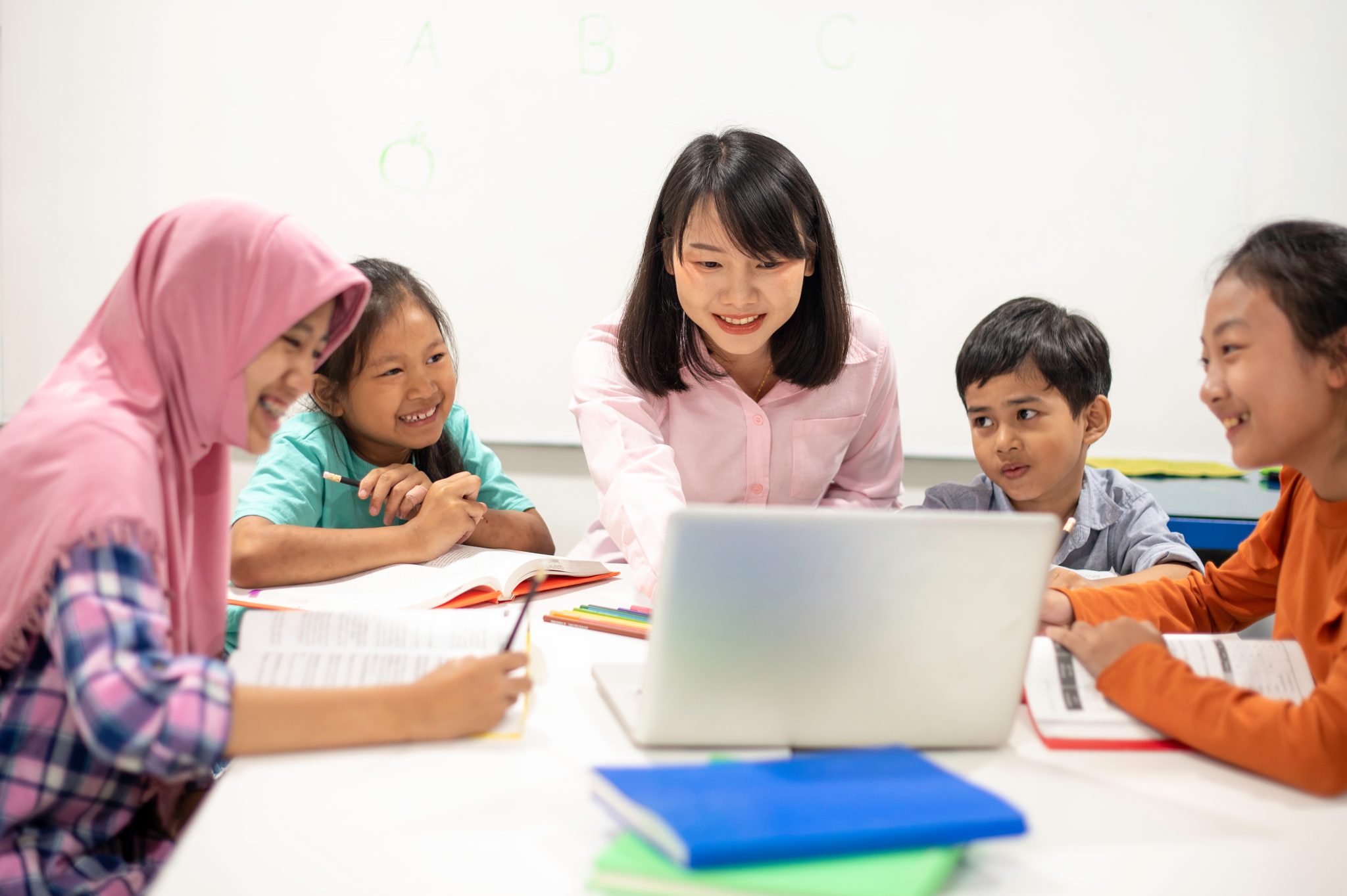 Image of a group of teachers and students looking at a laptop