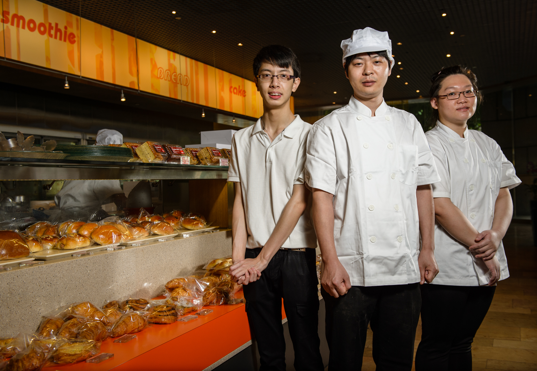 A trio of bakers pose and smile for the camera.