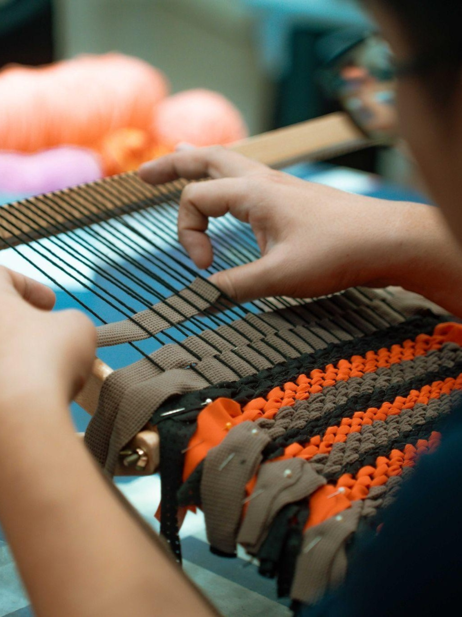 re-store-2 an individual holding up and interacting with the weaving equipment