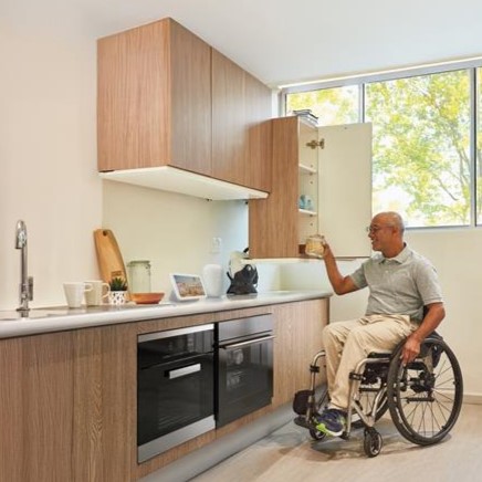 A wheelchair user reaching out for items in a kitchen.
