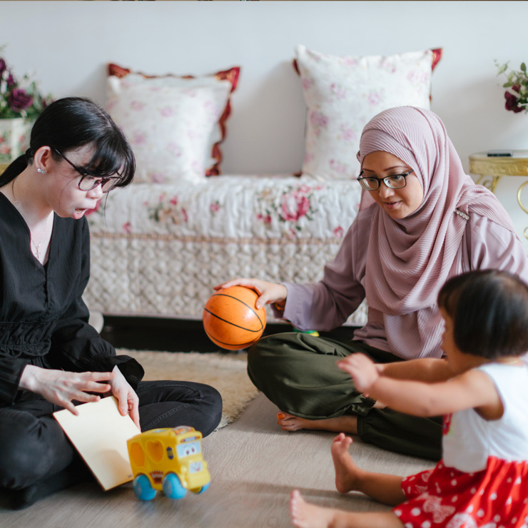 A teacher, a caregiver and her toddler with some toys in a learning setting at home.