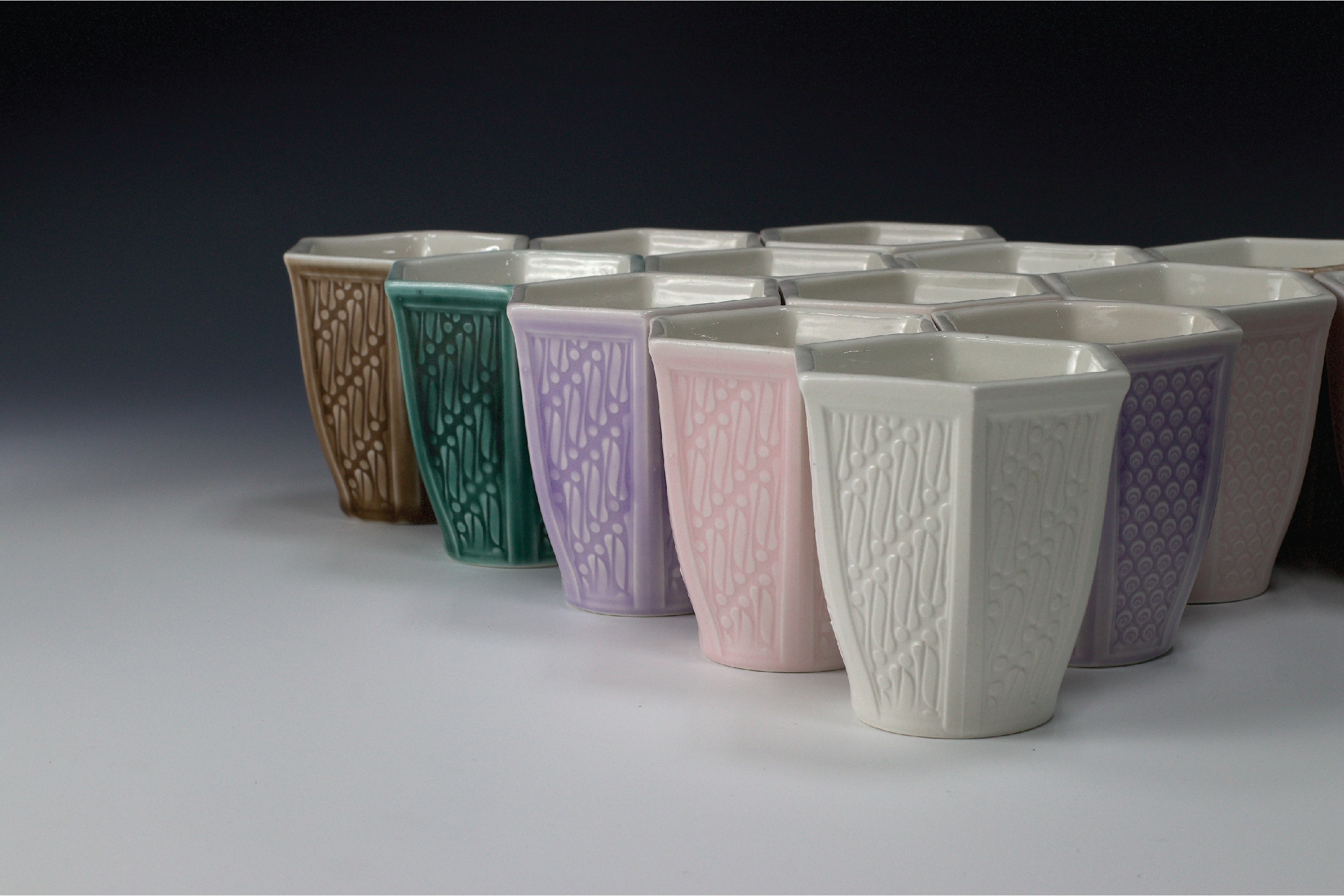 A dozen of ceramic cups in multiple colours.